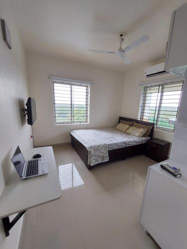 1 dormitorio con cama y escritorio con ordenador portátil en Kumars @udupi en Udupi