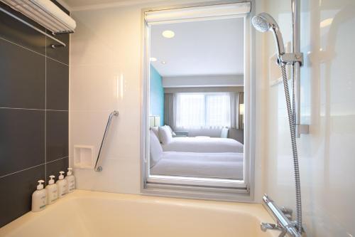 大阪的住宿－大阪難波假日酒店，带浴缸和镜子的浴室