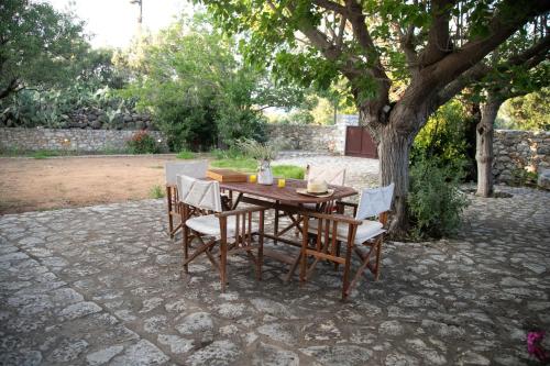 a wooden table and chairs under a tree at Anna's Garden in Triandafilliá