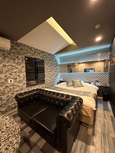 a bedroom with a bed and a leather couch at HOTEL EXE (Adult Only) in Tokyo