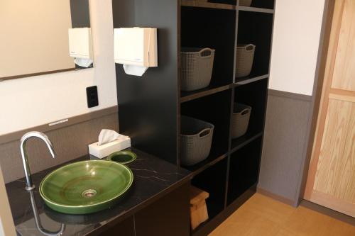 霧島的住宿－Shikisai no Sato Manyu，一间带绿色水槽和架子的浴室