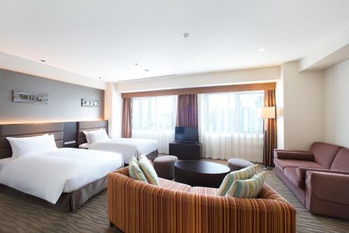 大阪市にあるホリデイ・イン大阪難波のベッド2台とソファが備わるホテルルームです。
