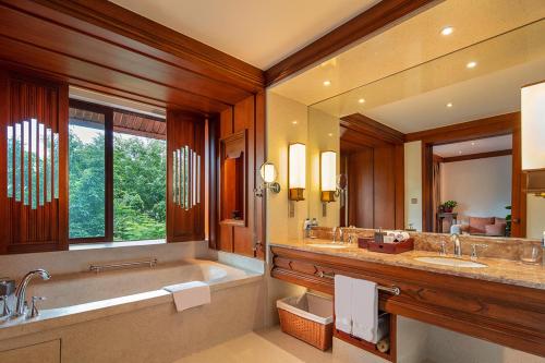 baño con 2 lavabos, bañera y espejo grande en Anantara Xishuangbanna Resort, en Jinghong