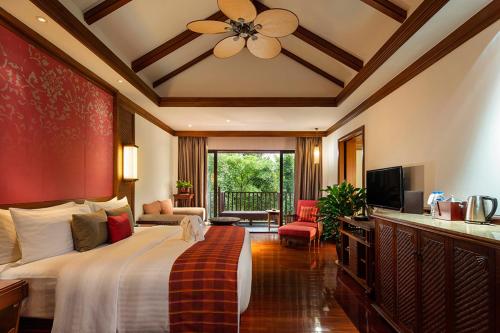 a hotel room with a bed and a television at Anantara Xishuangbanna Resort in Jinghong