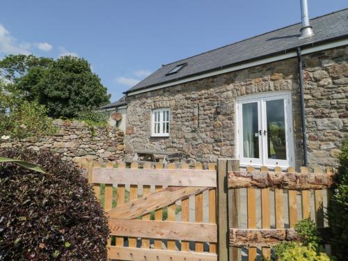 a stone cottage with a wooden fence at No 1 The Granary in Llangefni