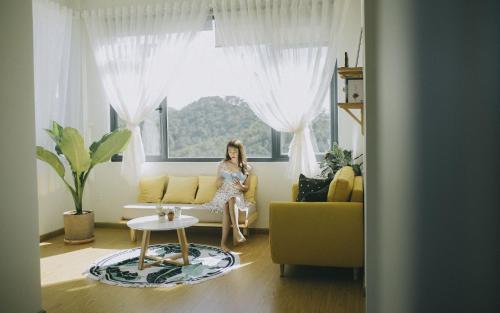 a woman sitting on a couch in a living room at Lux Nest Villa Đà Lạt in Da Lat