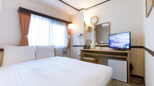 a hotel room with a bed and a desk with a television at Toyoko Inn Tokyo Kamata Higashi-guchi in Tokyo