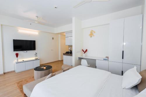 a white bedroom with a bed and a tv at Skystay Lucknow in Lucknow