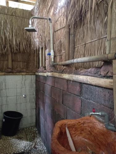 a dirty bathroom with a tub in a brick wall at Sumilir Riverside Retreat in Banyuwangi
