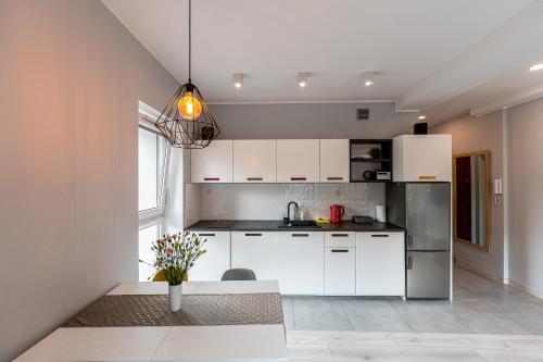 a kitchen with white cabinets and a stainless steel refrigerator at Emerald Apartament przy deptaku in Szczawno-Zdrój