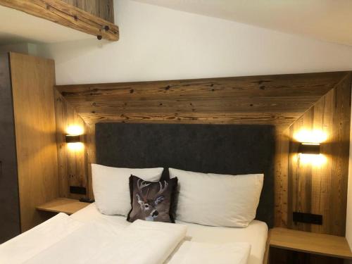 a bedroom with a white bed with a wooden headboard at Landhaus Thomas in Mayrhofen