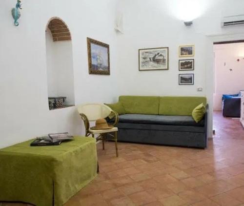 a living room with a green couch and a table at Casa Almagio - Atrani Amalfi coast - terrace & seaview in Atrani