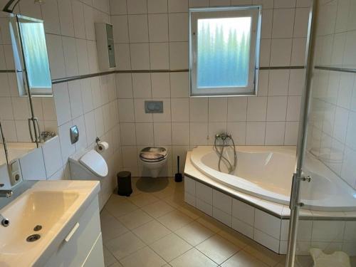 a bathroom with a tub and a toilet and a sink at Fehmarn Ahoi FamKreil bis 6,5 Pers in Fehmarn
