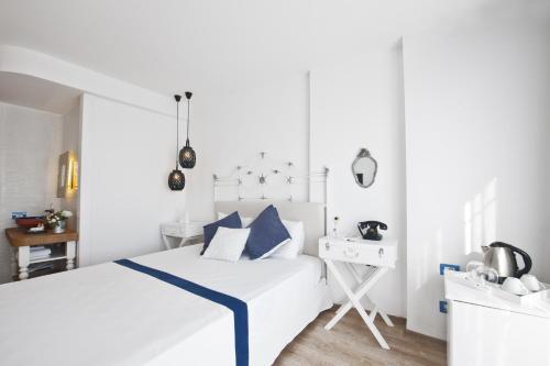 a white bedroom with a white bed with blue accents at Sade Alacati Hotel in Alaçatı