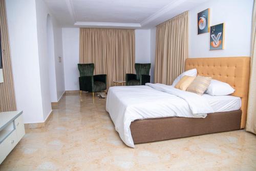 a bedroom with a large bed and two chairs at MOBAK APARTMENT in Lagos