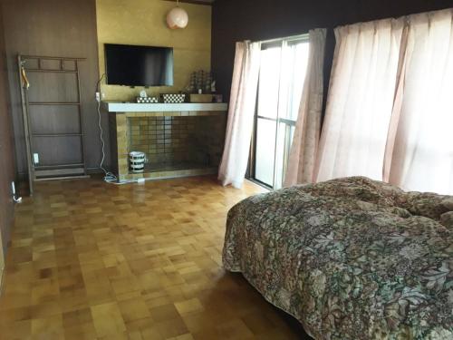 um quarto com uma cama, uma lareira e uma televisão em オーベルジュ鳴門 em Naruto
