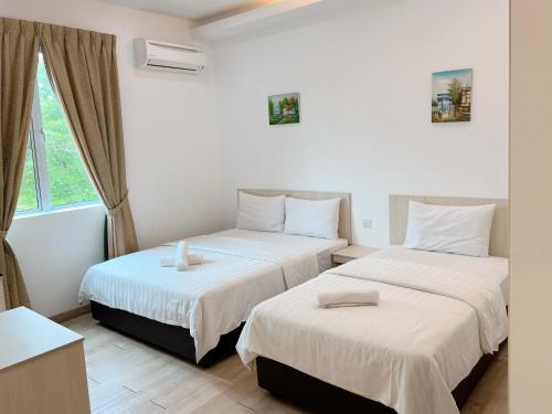twee bedden in een kamer met een raam bij Vvip Hotel in Hutan Melintang