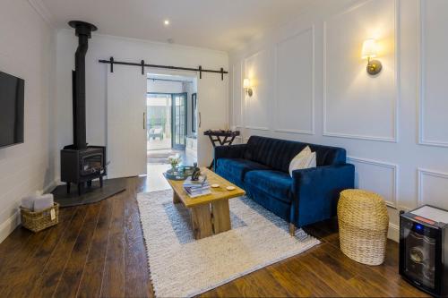 a living room with a blue couch and a wood stove at MAIN STREET RETREAT - King BRs, Comp Minibar, Breakfast Prov, Fireplaces in McLaren Flat