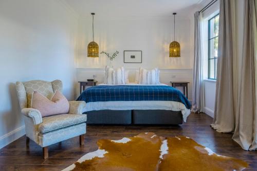 a bedroom with a bed and a chair and a couch at MAIN STREET RETREAT - King BRs, Comp Minibar, Breakfast Prov, Fireplaces in McLaren Flat