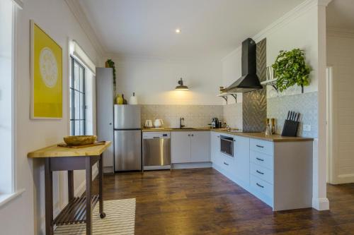 a large kitchen with white cabinets and a refrigerator at MAIN STREET RETREAT - King BRs, Comp Minibar, Breakfast Prov, Fireplaces in McLaren Flat