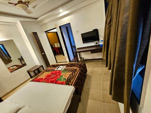 a hotel room with a bed and a table and a television at Suman Cottage & Bungalow in Mahabaleshwar