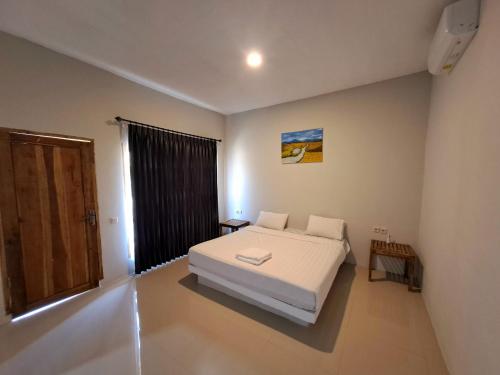 a bedroom with a white bed and a window at Village Corner Homestay in Kuta Lombok