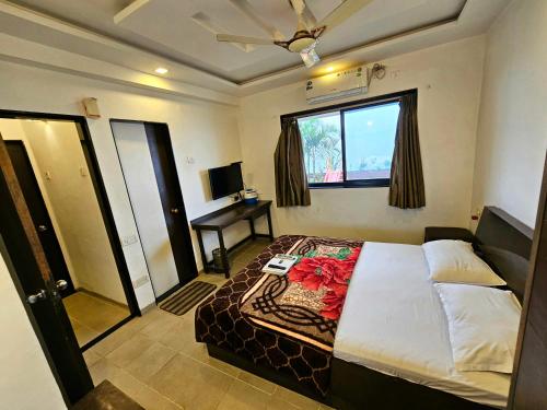 a bedroom with a bed and a window and a desk at Suman Cottage & Bungalow in Mahabaleshwar