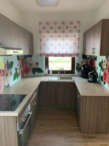 a kitchen with a sink and a window with a floral curtain at Casa Leda in Sovata