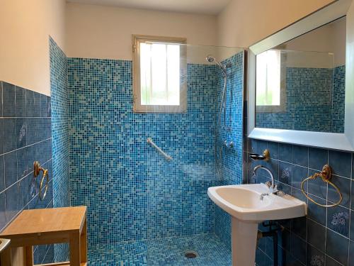 bagno piastrellato blu con lavandino e doccia di Casa Minnana a Figari