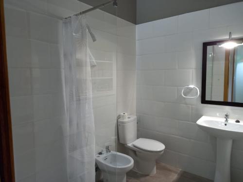 a white bathroom with a toilet and a sink at Ca Bastiana in La Piñera