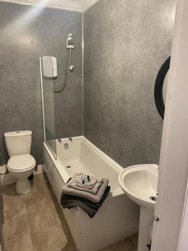 a bathroom with a tub and a toilet and a sink at Lovely 2 bedroom condo in Burntisland, Fife in Burntisland
