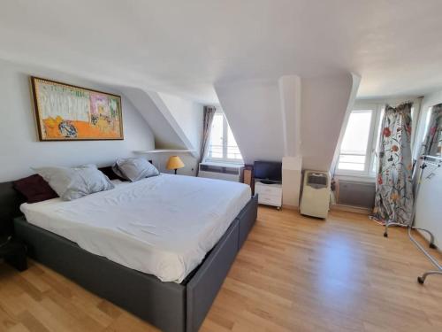 - une chambre avec un grand lit dans une pièce dotée de fenêtres dans l'établissement Superbe logement au centre de Paris, à Paris