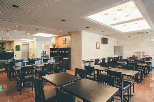 Kuretake-Inn Kakegawa في كاكِغو: غرفة طعام مليئة بالطاولات والكراسي