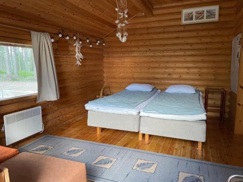 a bedroom with two beds in a log cabin at Kolmiloukon leirintäalue in Taivalkoski