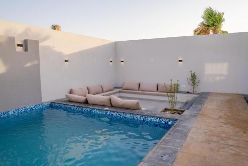 ein Wohnzimmer mit einem Sofa neben einem Pool in der Unterkunft منتجع دلال الفندقي Dalal Hotel Resort in Dammam