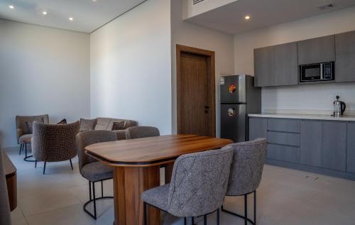 a kitchen with a wooden table and some chairs at منتجع دلال الفندقي Dalal Hotel Resort in Dammam