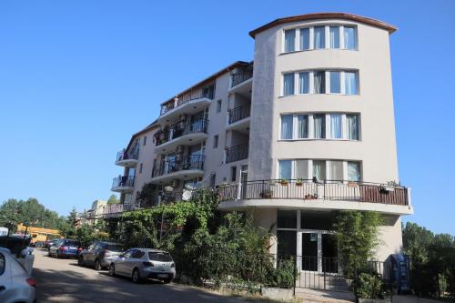 a tall white building with cars parked in front of it at Къща за гости "Arawana" in Sunny Beach