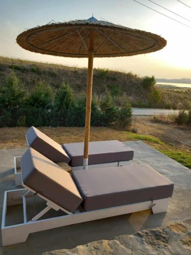 a pair of lounge chairs and an umbrella at Paliokaliva Home in Roussopoúlion