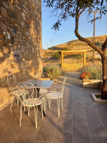 a patio with a table and chairs and a tree at Paliokaliva Home in Roussopoúlion