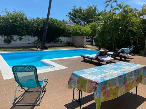 a table and chairs next to a swimming pool at Villa Laurier Rose avec piscine proche lagon de La Saline in La Saline les Bains