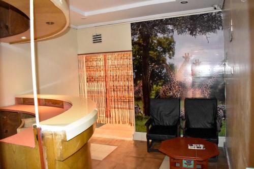 hol z dwoma krzesłami i obrazem na ścianie w obiekcie Sundowner Lodge w mieście Nakuru