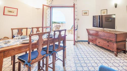 sala de estar con mesa, TV, mesa y sillas en Welcomely - Retiro Perpignan, en Alghero