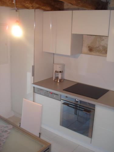 une cuisine avec des armoires blanches et un four à plaques de cuisson dans l'établissement Le pigeonnier, à Virac
