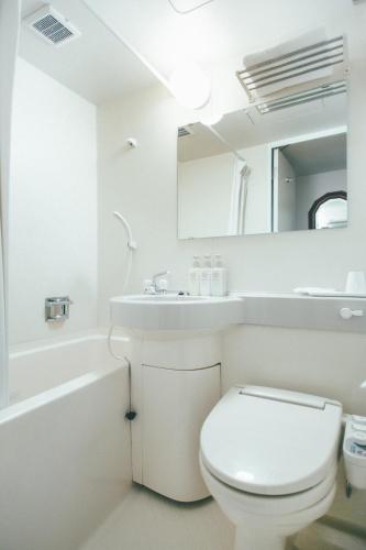 a white bathroom with a toilet and a sink at Kuretake-Inn Kakegawa in Kakegawa