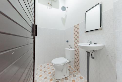 ein Badezimmer mit einem WC, einem Waschbecken und einem Spiegel in der Unterkunft Urbanview Hotel La De Grizz Syariah Sampit by RedDoorz in Sampit