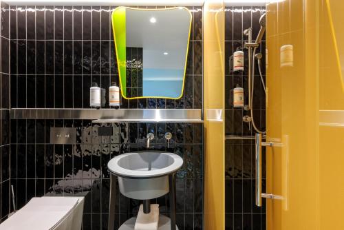 a bathroom with a sink and a mirror and a toilet at Adge Hotel and Residences in Sydney