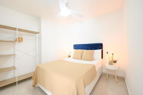 a white bedroom with a bed with a blue headboard at Burgos 2 Terrace, pool, parking by 10ToSea in Fuengirola