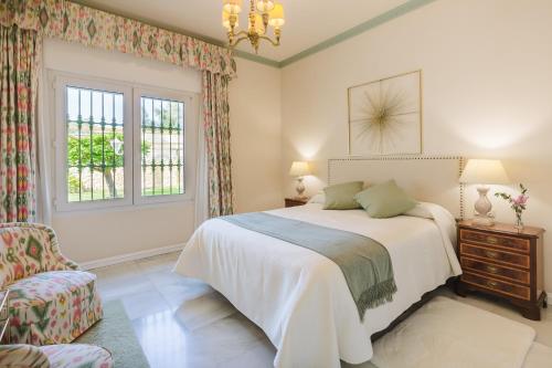 una camera con un letto e una sedia e una finestra di Villa Galemar Pool & Gardens a Torremolinos