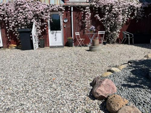 a house with a gravel yard with a door and flowers at Marielyst, idyllisk feriehus 800m fra torvet in Bøtø By