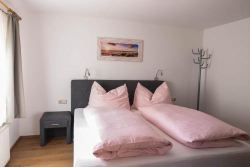 Una cama con sábanas rosas y almohadas. en Appartements Gadenstätter en Maria Alm am Steinernen Meer